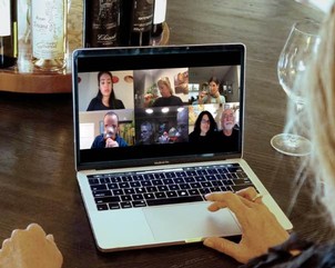 A Virtual Guided Wine Tasting with attendees in a Zoom meeting grid on a laptop screen with wine bottles in the background.