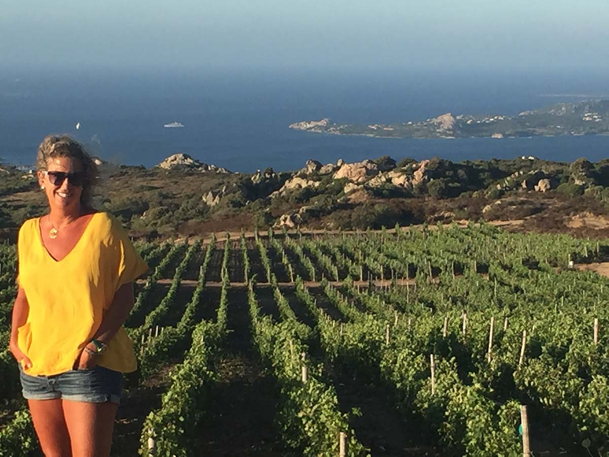 Nina Snow, Owner of DOCG Imports, standing in a Sardinian vineyard overlooking the Mediterranean Sea